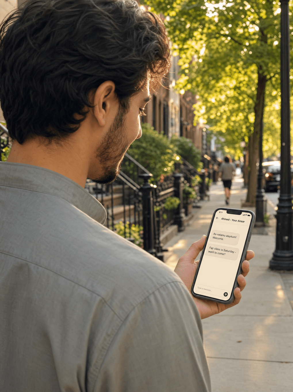 A New Muslim out in the city reading a message from their Ansar in the Ansar Family portal on their phone.